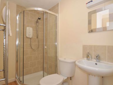 A bathroom with a shower, toilet, and sink at 9 Slipway Cottages, Rock