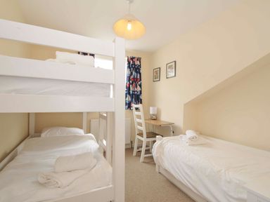 A bedroom with bunk bed and single bed at 9 Slipway Cottages, Rock