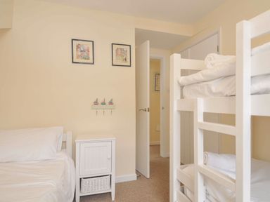 A bedroom with a bunk bed and single bed at 9 Slipway Cottages Rock