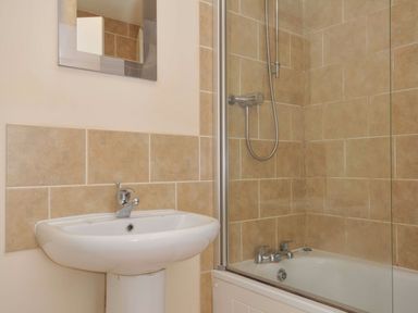 A bathroom with a wash basin and a bathtub at 9 Slipway Cottages in Rock