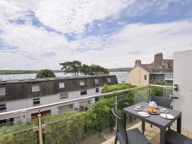 A balcony with a table and chairs overlooking the water at 9 Slipway Cottages in Rock