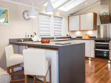 A kitchen with a counter and stools at The Maples 44 St. Austell