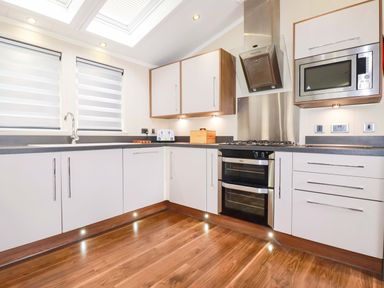 A kitchen with white cabinets and appliances at The Maples 44 in St. Austell