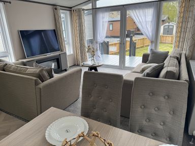 A living room with a sofa, television, and table at Lime Tree Lodge