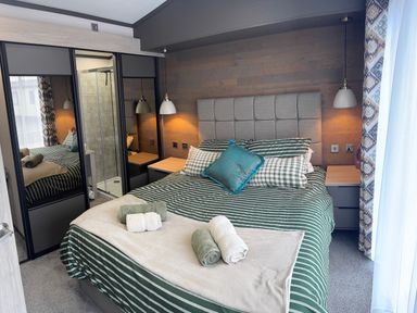 A bedroom with a bed and wardrobe at Lime Tree Lodge St Fillans