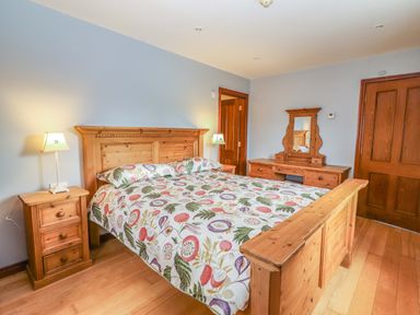 A bedroom with a wooden bed and dresser at Ash House in Ballyvaughan