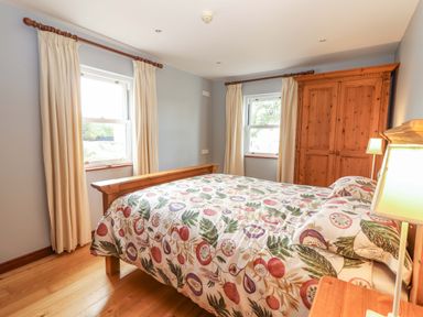 A bedroom with a bed, a wardrobe, and a lamp at Ash House in Ballyvaughan