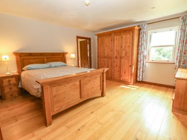 A bedroom with a bed and wardrobe at Ash House Ballyvaughan