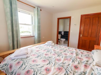 A bedroom with a bed and an adjoining bathroom at Ash House in Ballyvaughan