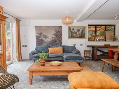 A living room with a sofa, coffee table, and artwork at Tigley Meadow Coach House in Totnes