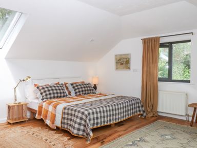 A bedroom with a bed and window at Tigley Meadow Coach House in Totnes