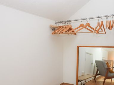 A wardrobe with hangers and a mirror at Tigley Meadow Coach House in Totnes