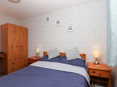 A bedroom with a bed, bedside tables, a wardrobe and wall art at Boo’s Bungalow in Callington near Gunnislake