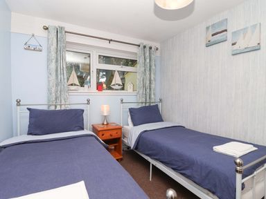 A bedroom with two beds and a window at Boo’s Bungalow in Callington near Gunnislake