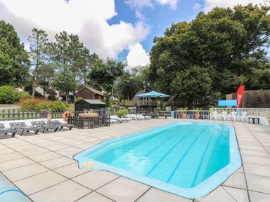 An outdoor swimming pool area with sun loungers at Boo’s Bungalow Callington near Gunnislake