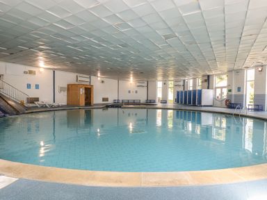 An indoor pool with seating and changing facilities at Boo’s Bungalow in Callington near Gunnislake