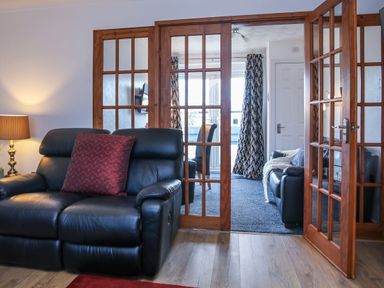 A living room with a sofa and doors at Penrhos Walks in Holyhead