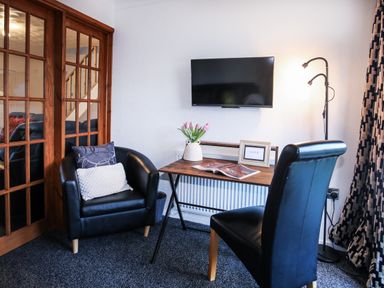 An office space with two chairs, a table, and a television at Penrhos Walks in Holyhead