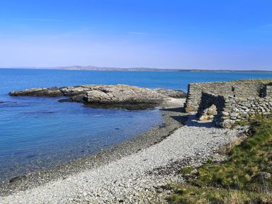 A beach with rocks and ruins at Penrhos Walks in Holyhead