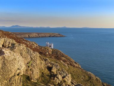 A coastal view featuring cliffs and a white building at Penrhos Walks Holyhead