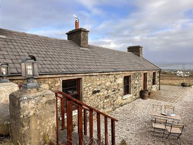 A cottage with stone walls and outdoor seating at Cobble Stone Cottage near Leabgarrow, County Donegal