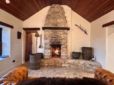 A living room with a stone fireplace and wooden features at Cobble Stone Cottage near Leabgarrow, County Donegal
