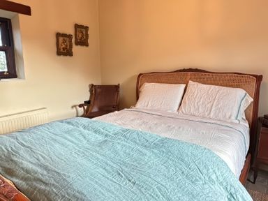 A bedroom with a bed and an armchair at Cobble Stone Cottage near Leabgarrow, County Donegal