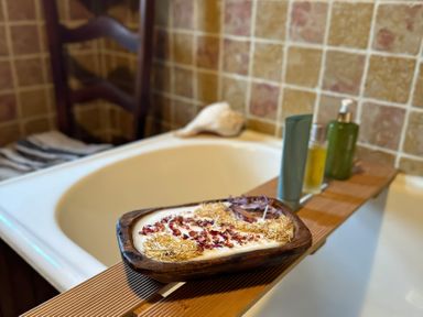 A bathtub with a wooden tray holding candles and bottles at Cobble Stone Cottage near Leabgarrow, County Donegal