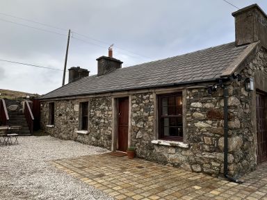 A stone cottage with a paved area and outdoor furniture at Cobble Stone Cottage near Leabgarrow, County Donegal