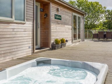 An outdoor area with a hot tub and seating at Two Tree Tops in Lanreath