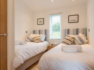 A bedroom with two beds, pillows and a window at 2 Tree Tops in Lanreath
