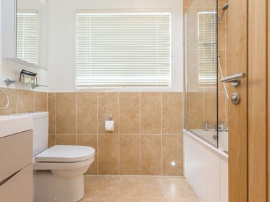 A bathroom with a toilet and bathtub at 2 Tree Tops in Lanreath
