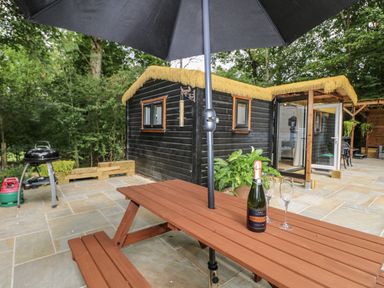 An outdoor area with a table, champagne, and cabins at Charltons Hollow Cabin in Haywards Heath