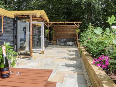 A garden with a cabin, outdoor seating, and plants at Charltons Hollow Cabin in Haywards Heath