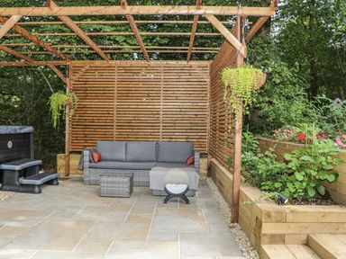 An outdoor seating area with a sofa and hot tub at Charltons Hollow Cabin in Haywards Heath