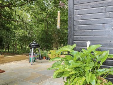 A garden area with a barbeque grill and plants at Charltons Hollow Cabin, Haywards Heath