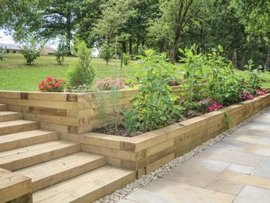 Garden with wooden steps and flower beds at Charltons Hollow Cabin in Haywards Heath