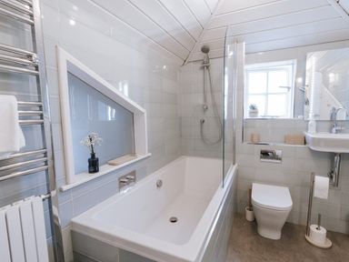 A bathroom with a bathtub, shower, toilet, and sink at Tamarisk Cottage in St. Agnes