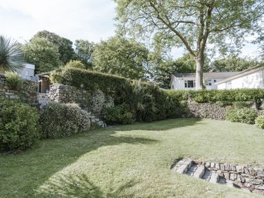 A garden with grass and stone features at Tamarisk Cottage in St. Agnes