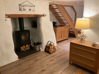 A living room featuring a wood stove and wooden cabinet at Tamarisk Cottage St Agnes