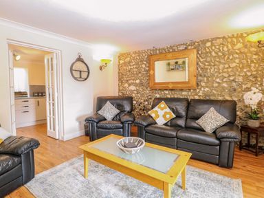 A living room with sofa and table at Honeysuckle Cottage in Swaffham