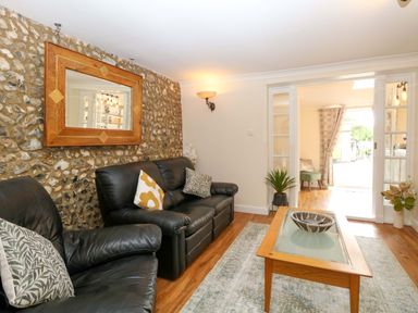 A living room with a sofa and coffee table at Honeysuckle Cottage in Swaffham