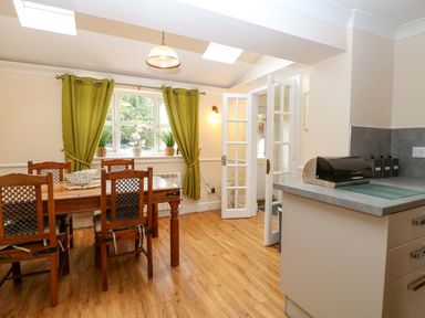A dining room with a table and chairs at Honeysuckle Cottage in Swaffham