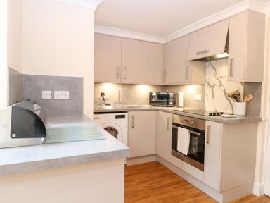 A kitchen with cabinets and appliances at Honeysuckle Cottage in Swaffham