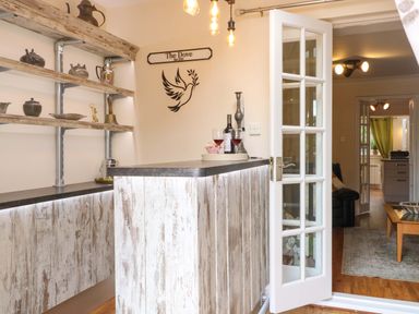 A kitchen with a bar and shelves at Honeysuckle Cottage in Swaffham