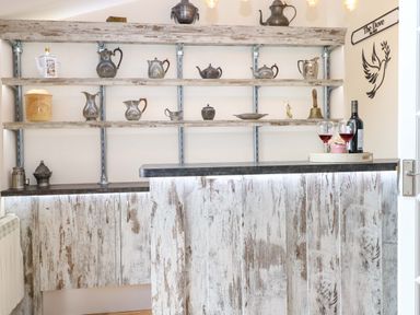 A bar with shelves displaying various items at Honeysuckle Cottage in Swaffham