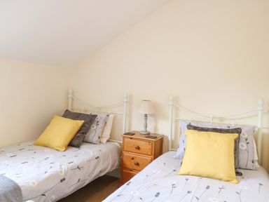 A bedroom with two beds and a lamp at Honeysuckle Cottage in Swaffham