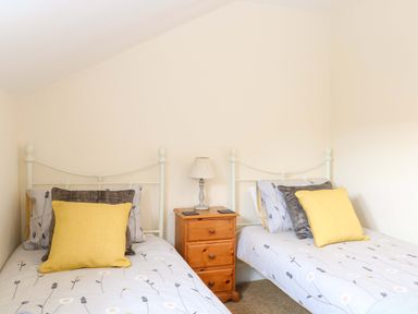 A bedroom with two single beds and a nightstand at Honeysuckle Cottage in Swaffham