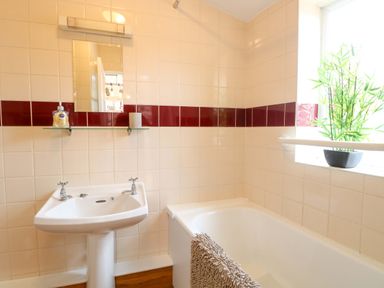A bathroom with a sink and bathtub at Honeysuckle Cottage in Swaffham