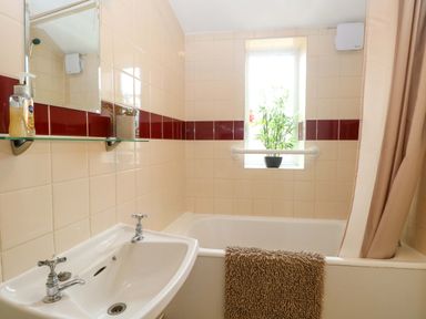 A bathroom with a sink and bathtub at Honeysuckle Cottage in Swaffham